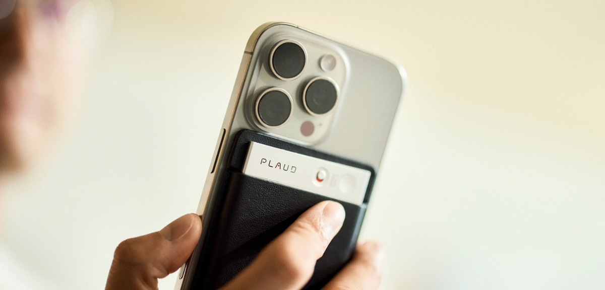 PLAUD NOTE AI voice recorder attached to the back of a smartphone, showing its slim design and recording switch.