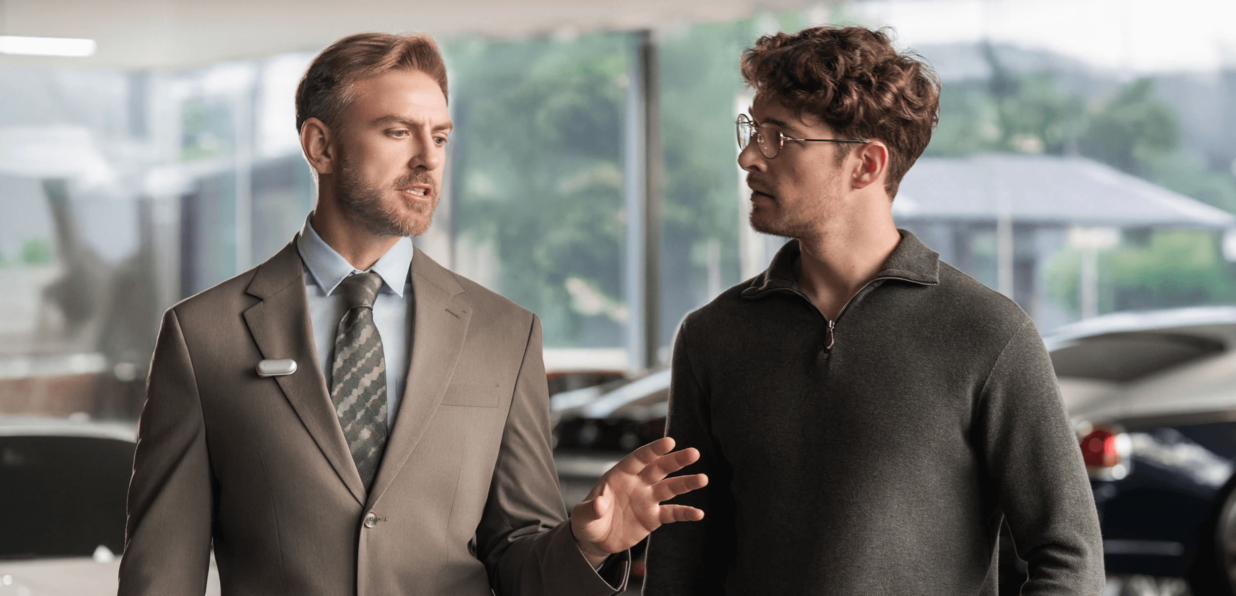 Professional wearing a Plaud NotePin on his suit lapel while conversing with a client in a showroom.