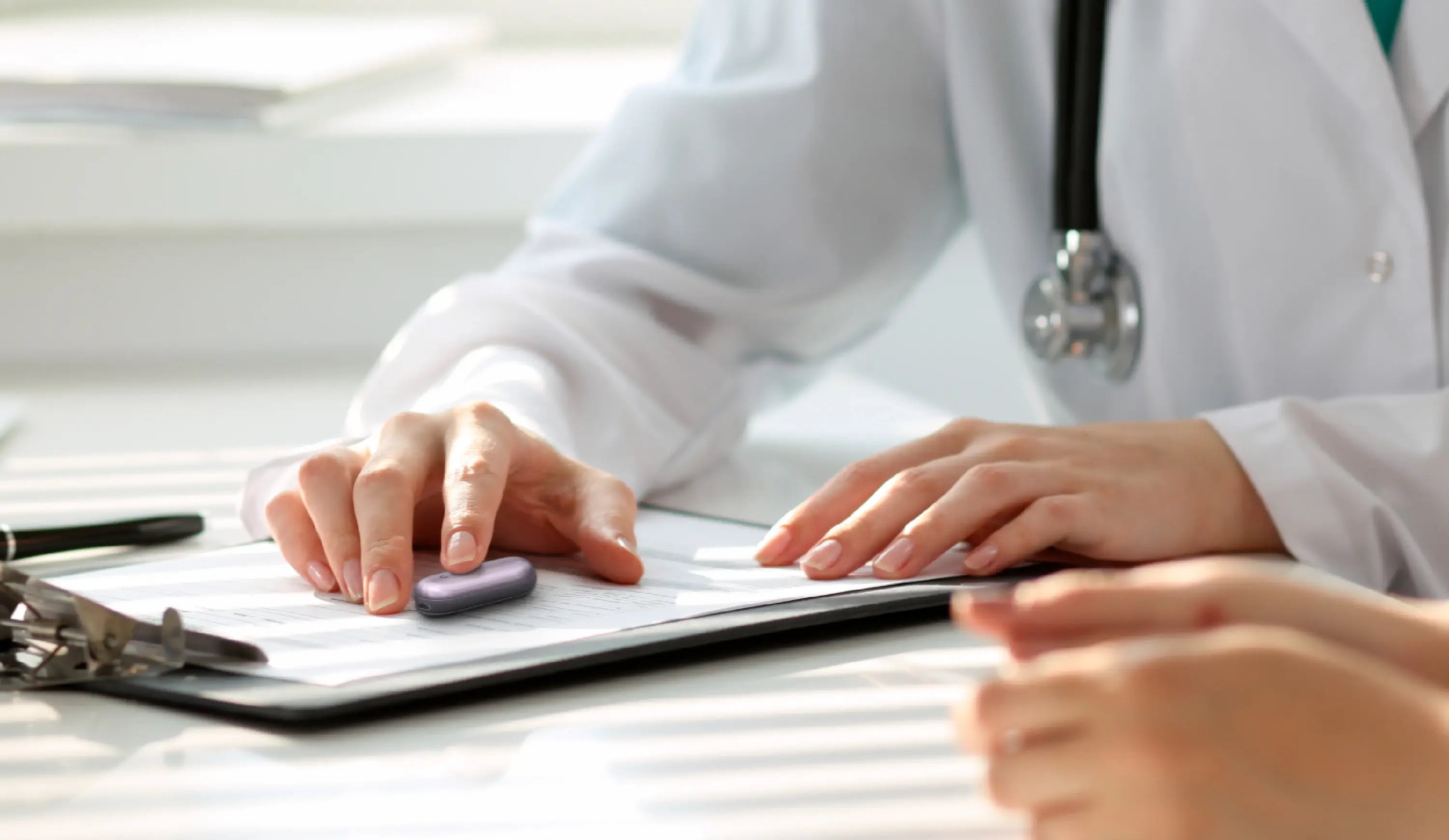 Medical professional using a Plaud NotePin to record notes during a consultation.