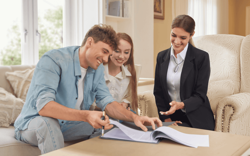 A professional wearing a Plaud NotePin records a consultation with a couple signing documents.
