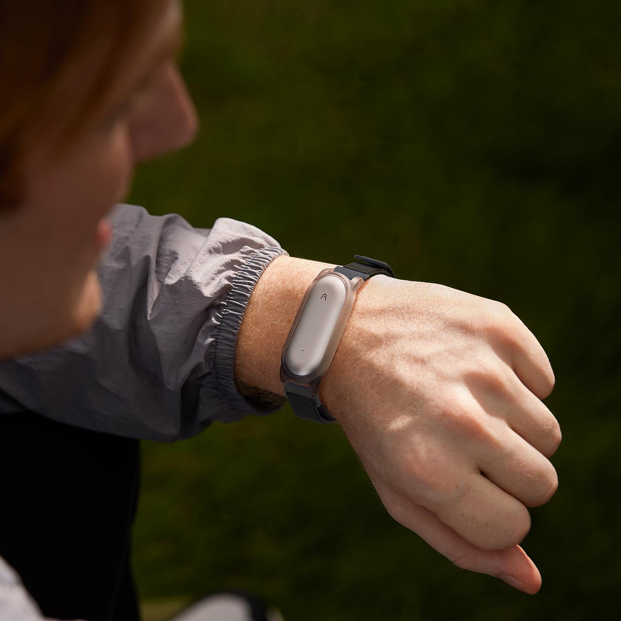 Person wearing the Plaud NotePin AI voice recorder on a wrist strap, showcasing its wearable design.