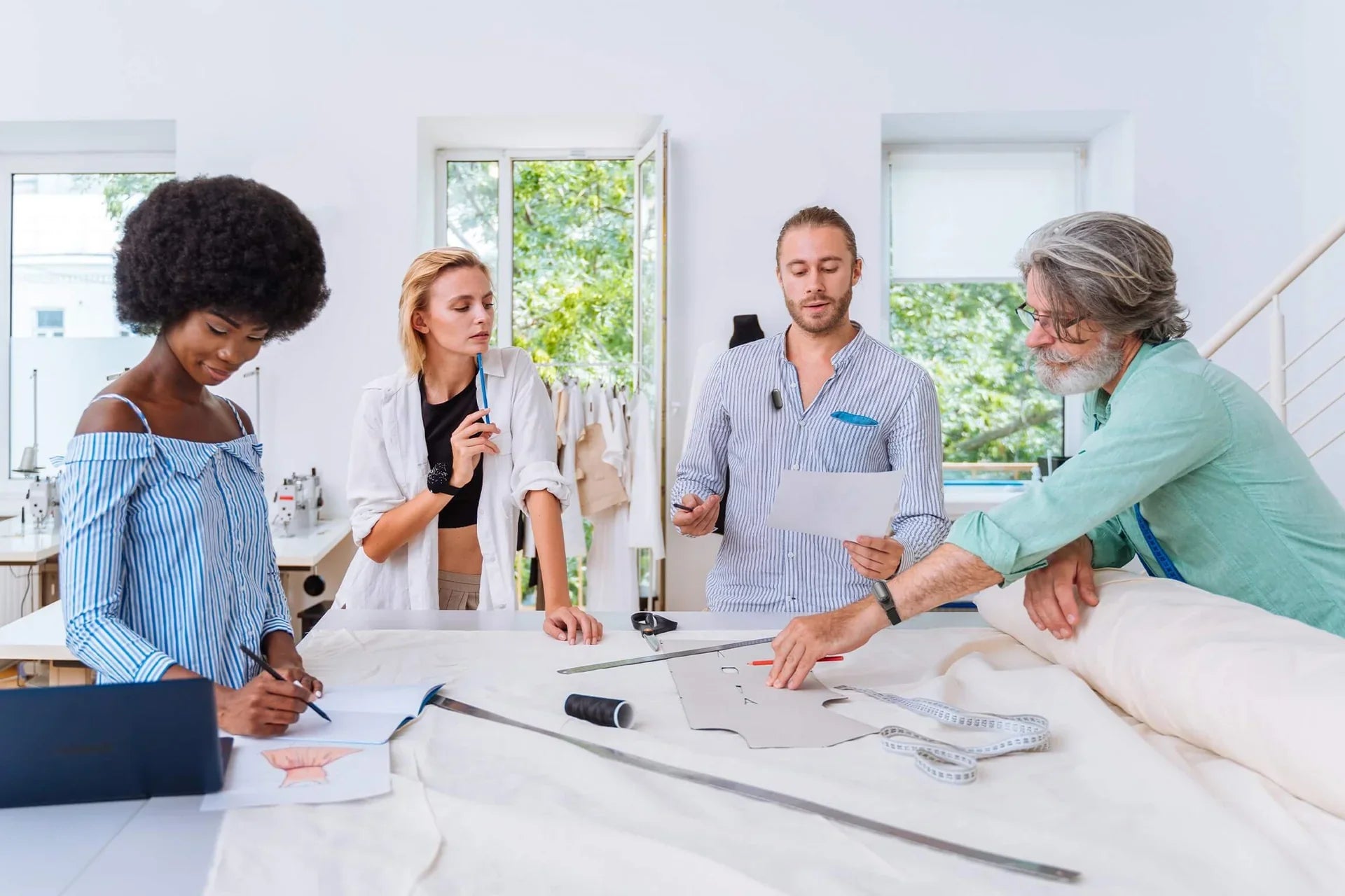Designers collaborating in a studio while a man wears a Plaud NotePin to capture ideas and notes.