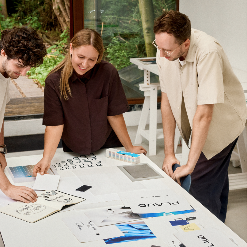 Three designers collaborating on Plaud product development and branding in a bright studio.