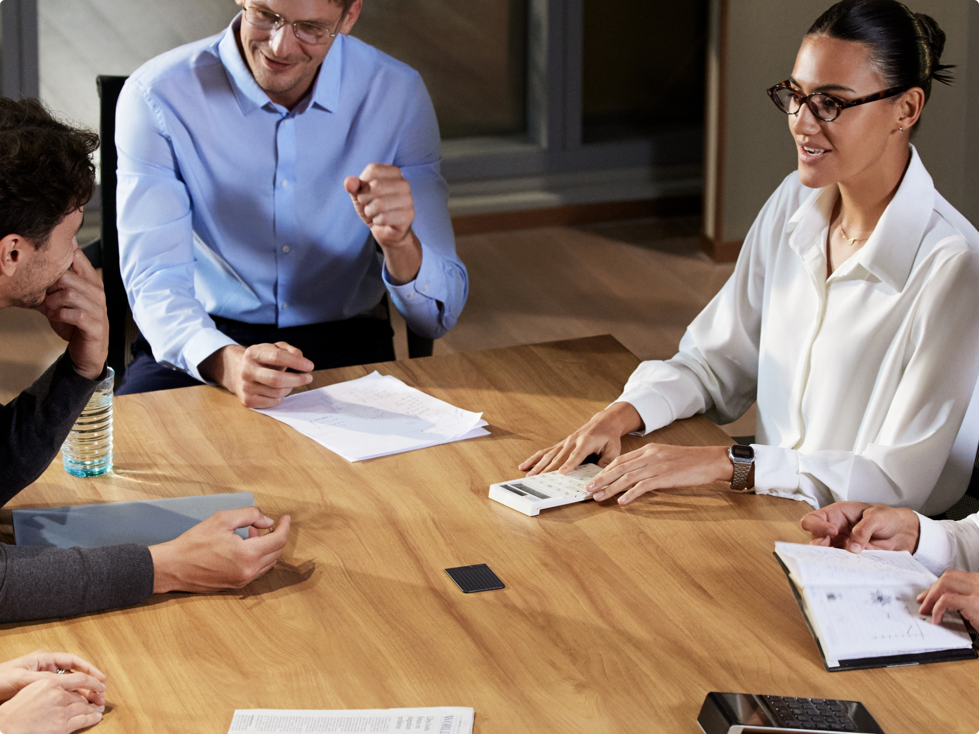 Professionals discuss ideas around a table with a Plaud NOTE AI voice recorder capturing the conversation.