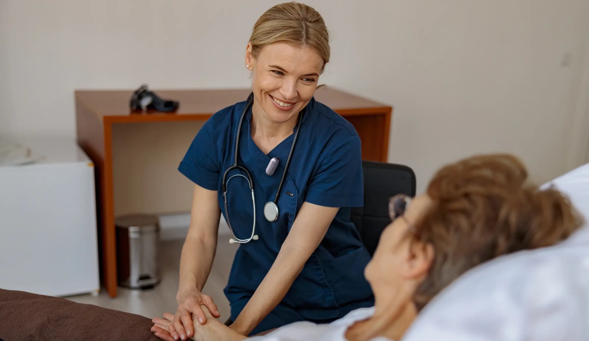 A nurse wearing the Plaud NotePin AI voice recorder while attending to a patient.