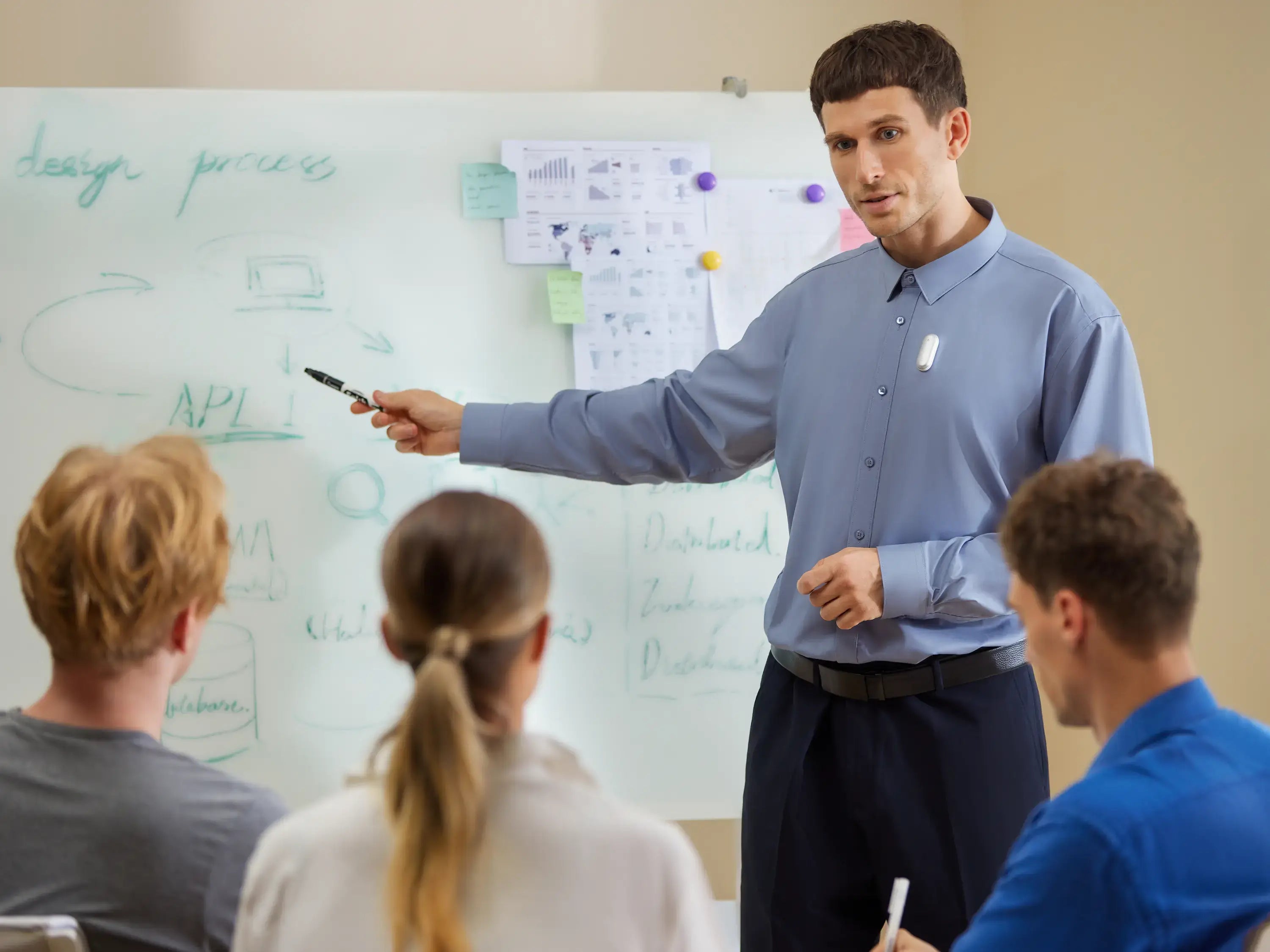 A man wearing a Plaud NotePin on his shirt while presenting to a group in front of a whiteboard.