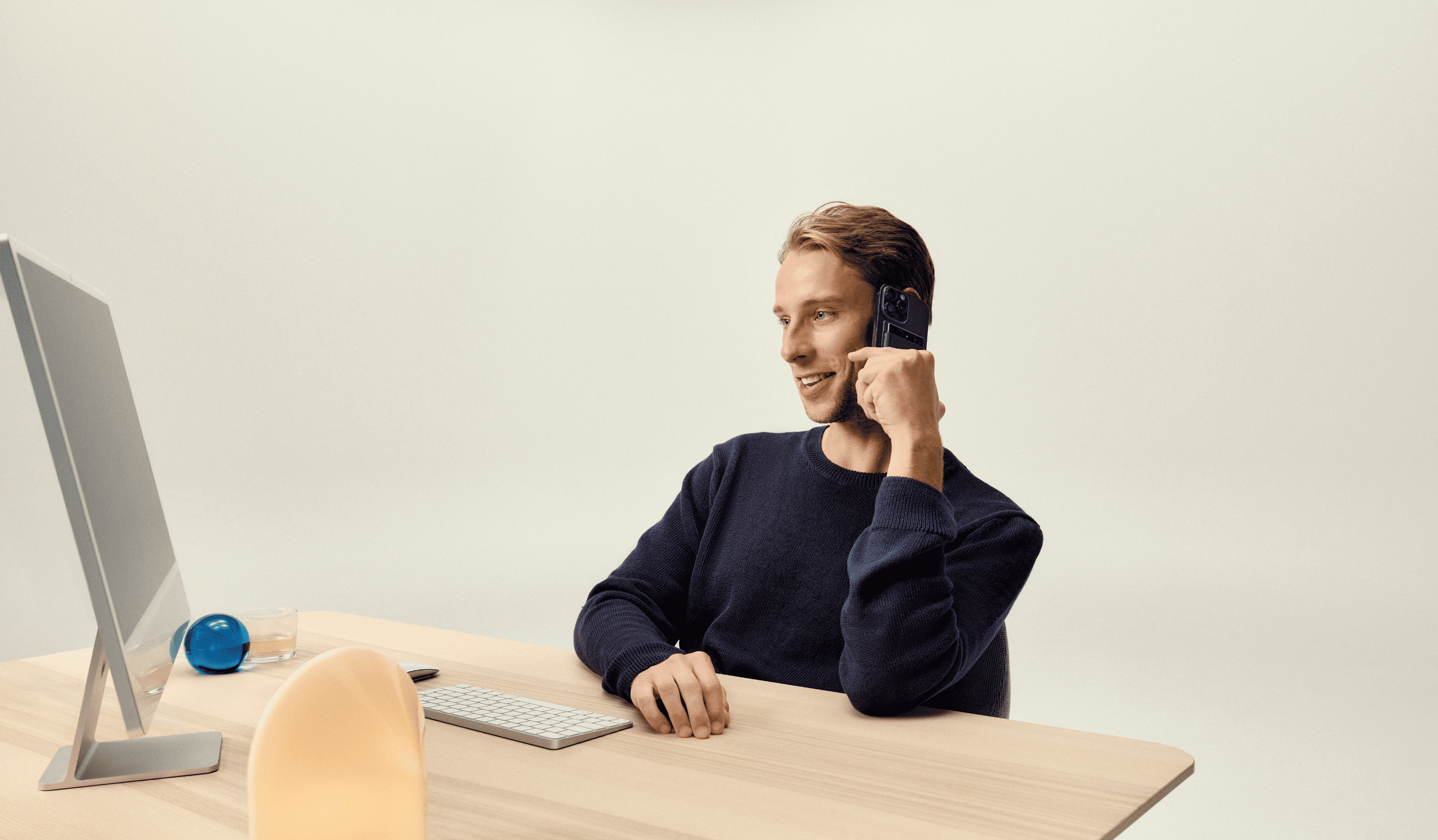 A man smiling while recording a phone call with a PLAUD NOTE AI voice recorder attached to his smartphone.