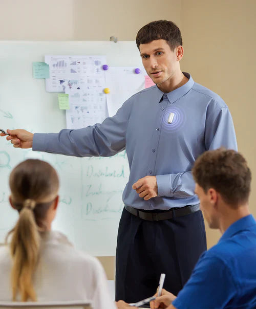 A professional wearing the Plaud NotePin on his shirt to record a meeting while presenting at a whiteboard.