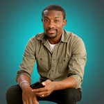 A man in a green shirt holding a smartphone against a teal background.