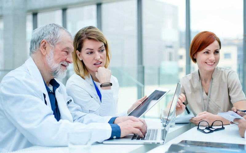 Medical professionals in a meeting, with one wearing a Plaud NotePin on her wrist to capture notes.
