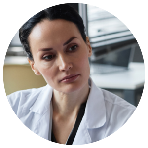 A female medical professional in a white coat looking focused and attentive.