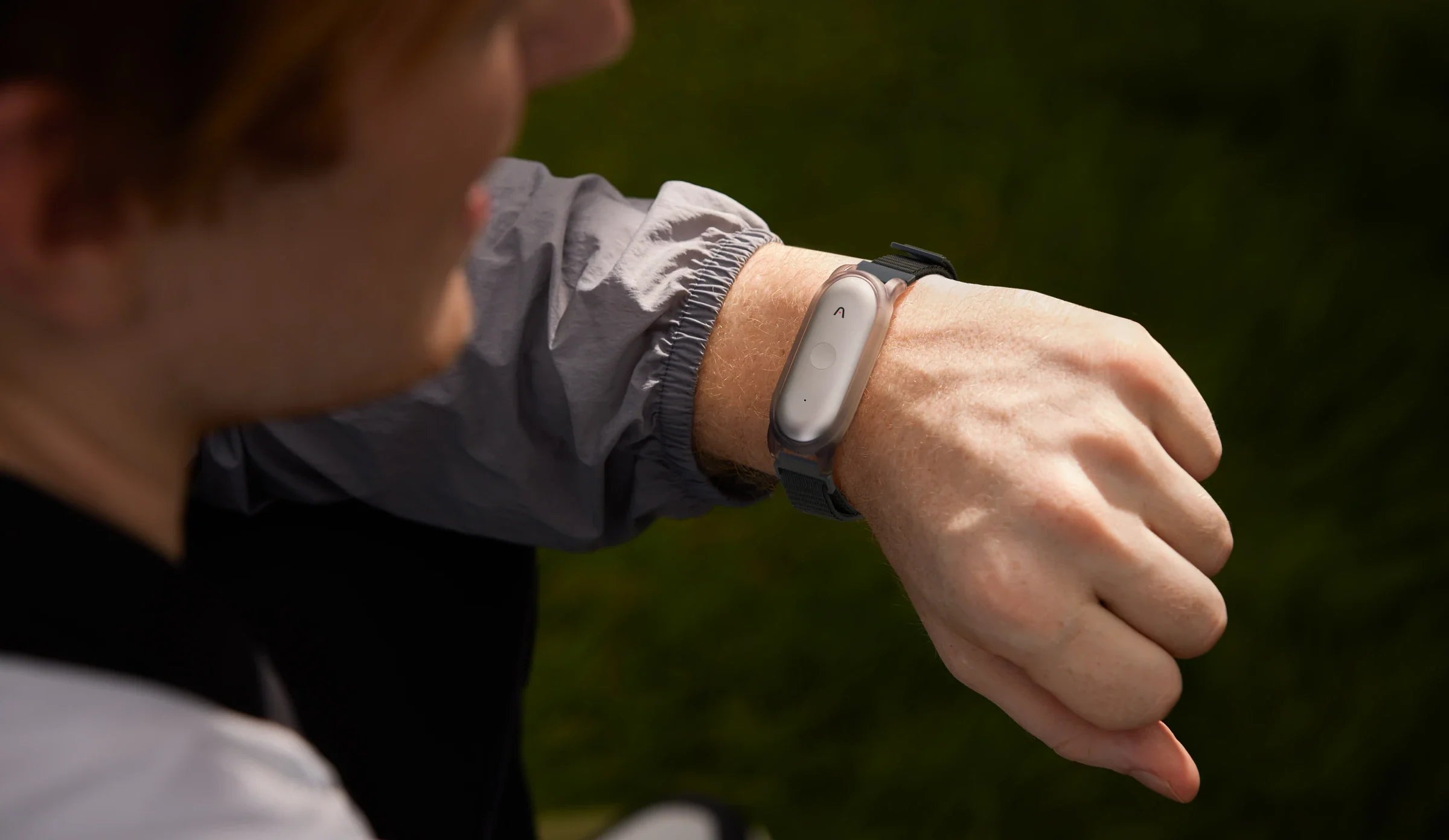 A person wearing the Plaud NotePin AI voice recorder on their wrist with a black watch band.