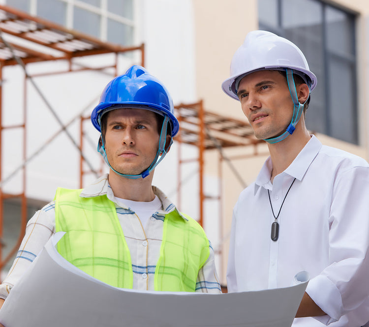 Two construction professionals reviewing blueprints, with one wearing a Plaud NotePin around his neck.