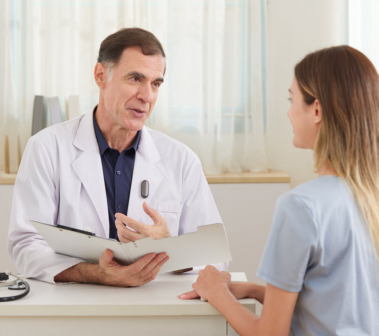 A doctor wearing the Plaud NotePin on his lapel during a patient consultation.