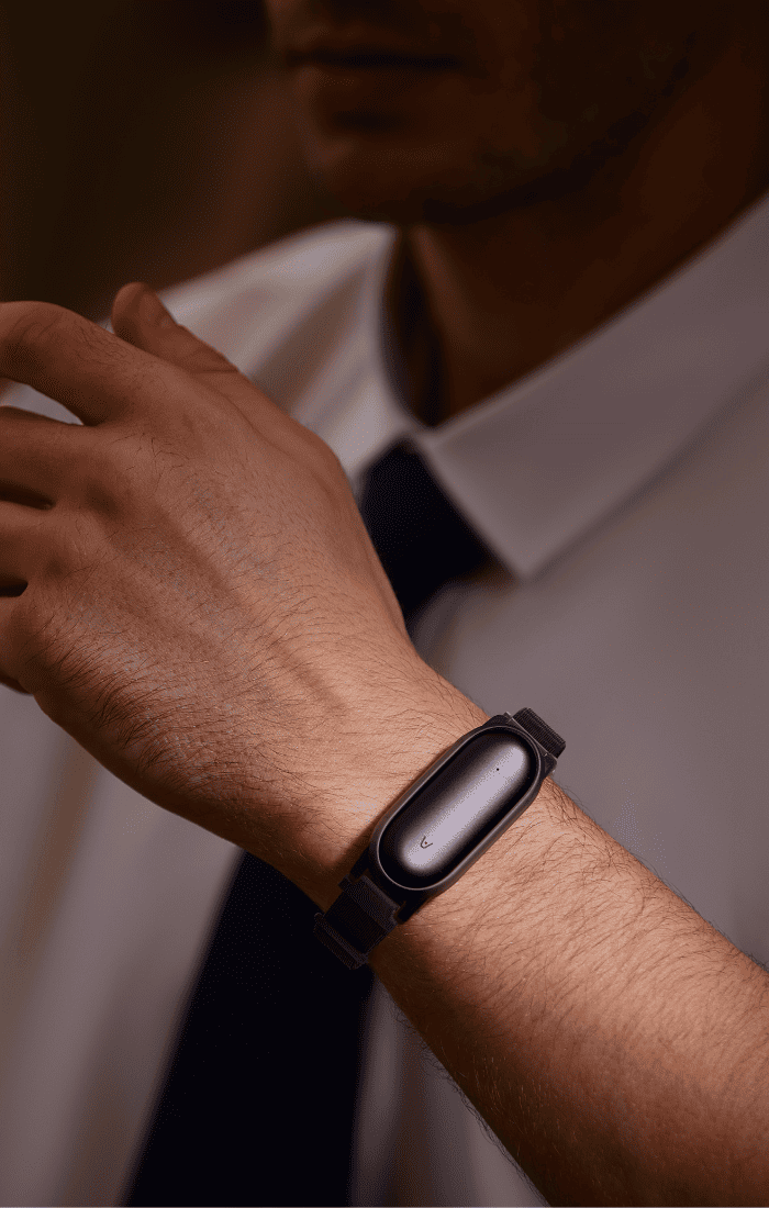 PLAUD NotePin AI voice recorder worn as a wristband by a man in professional attire.