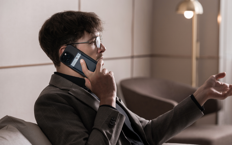 Professional using a Plaud Note on the back of a smartphone to record a phone call.
