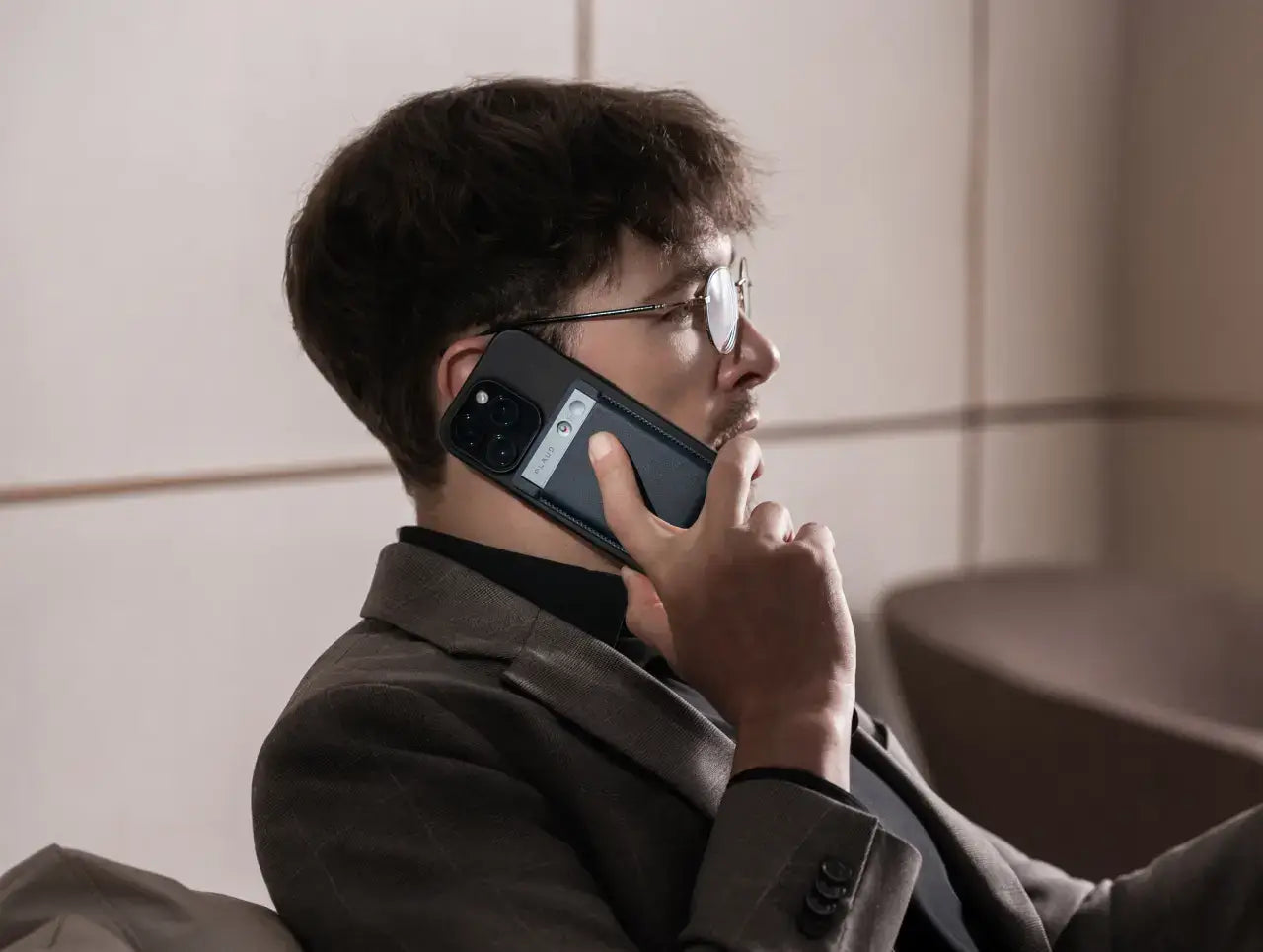 Man recording a phone call with the Plaud Note AI voice recorder attached to the back of his smartphone.