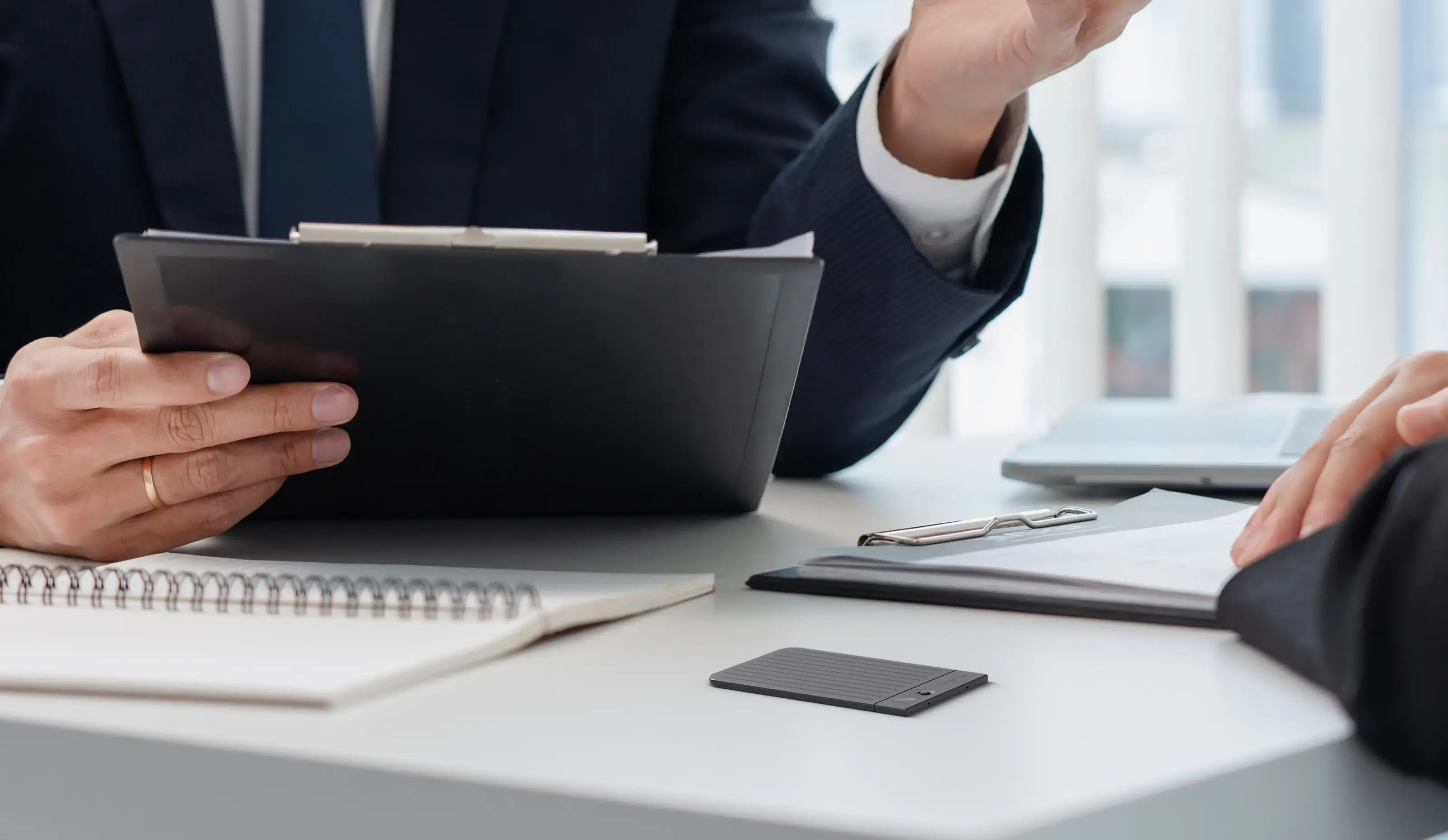 PLAUD NOTE AI voice recorder on a desk during a professional business meeting to capture and transcribe notes.