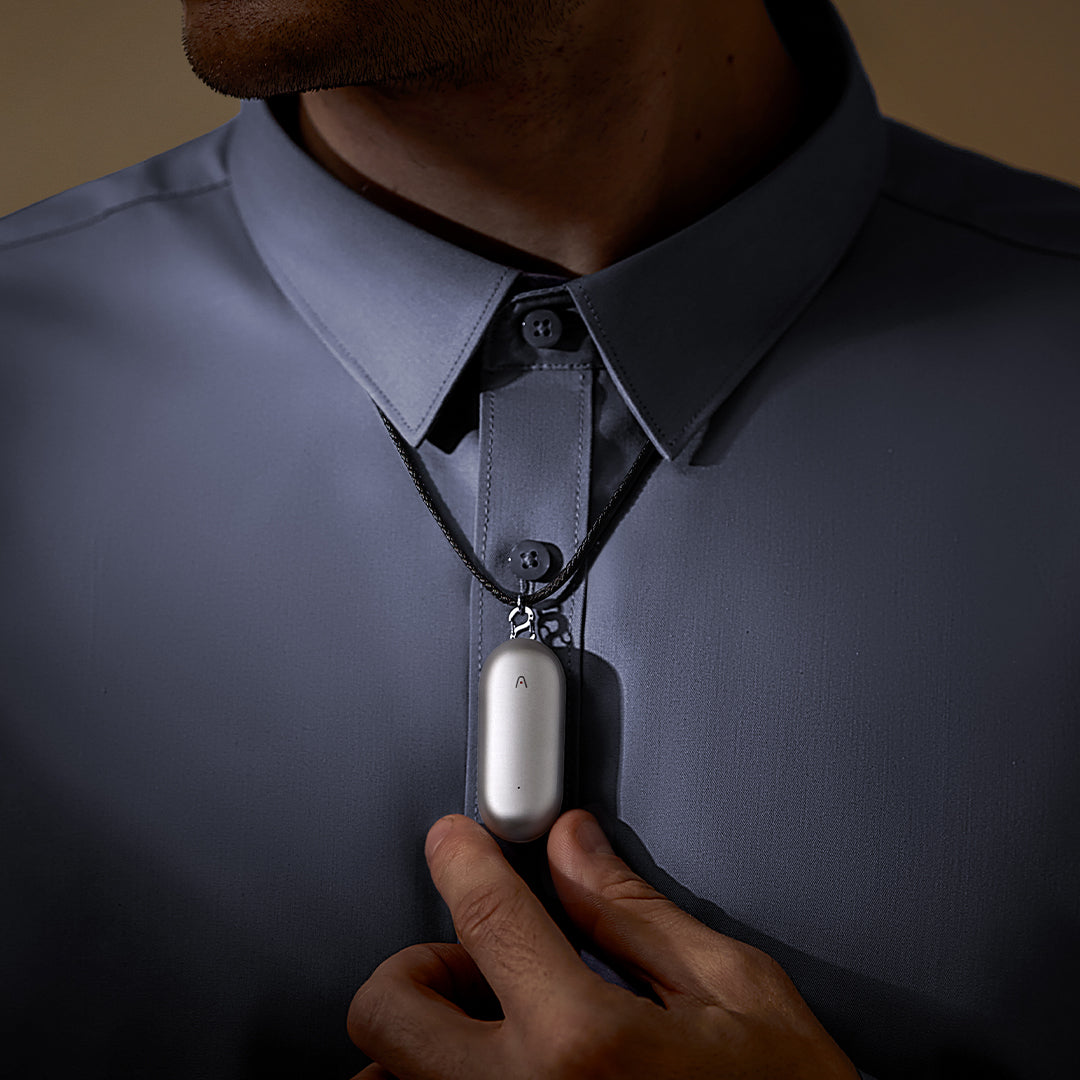 A person wearing the silver Plaud NotePin as a necklace, demonstrating its wearable AI voice recorder design.