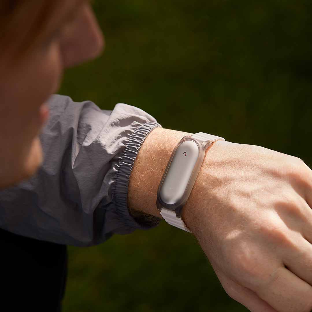 Plaud NotePin AI voice recorder worn on a wrist with a white strap, showcasing its portable, wearable design.