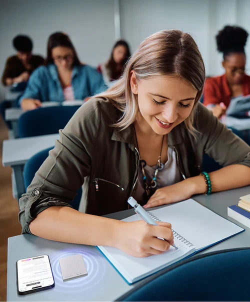 A student takes notes in class while a Plaud Note AI voice recorder captures the lecture on her desk.