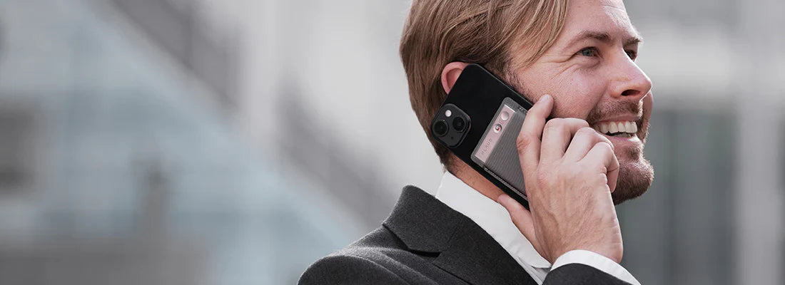 Man recording a phone call with a Plaud Note AI voice recorder attached to the back of his smartphone.