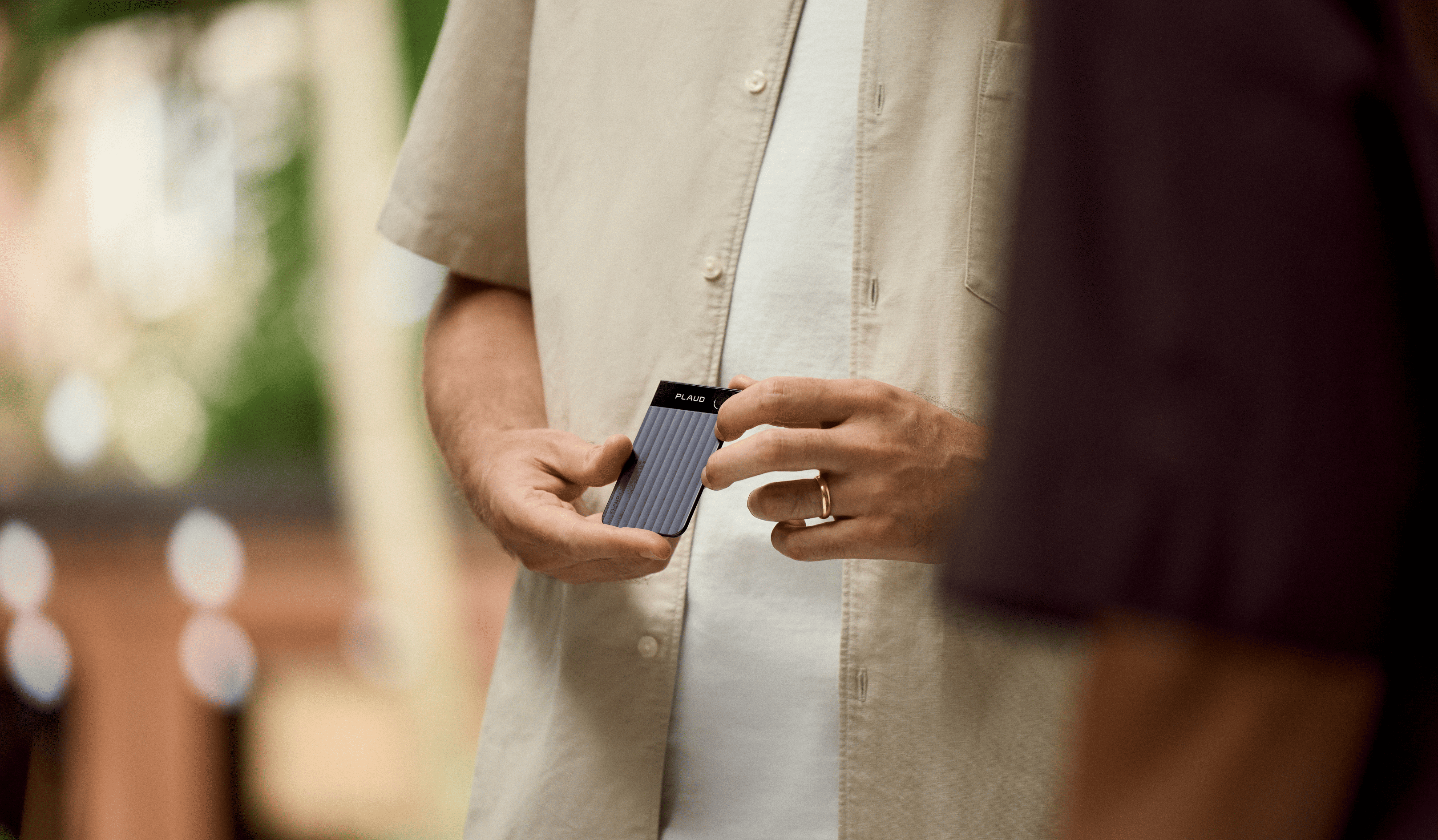 A person holding the slim PLAUD NOTE AI voice recorder, showcasing its compact and portable card-like design.
